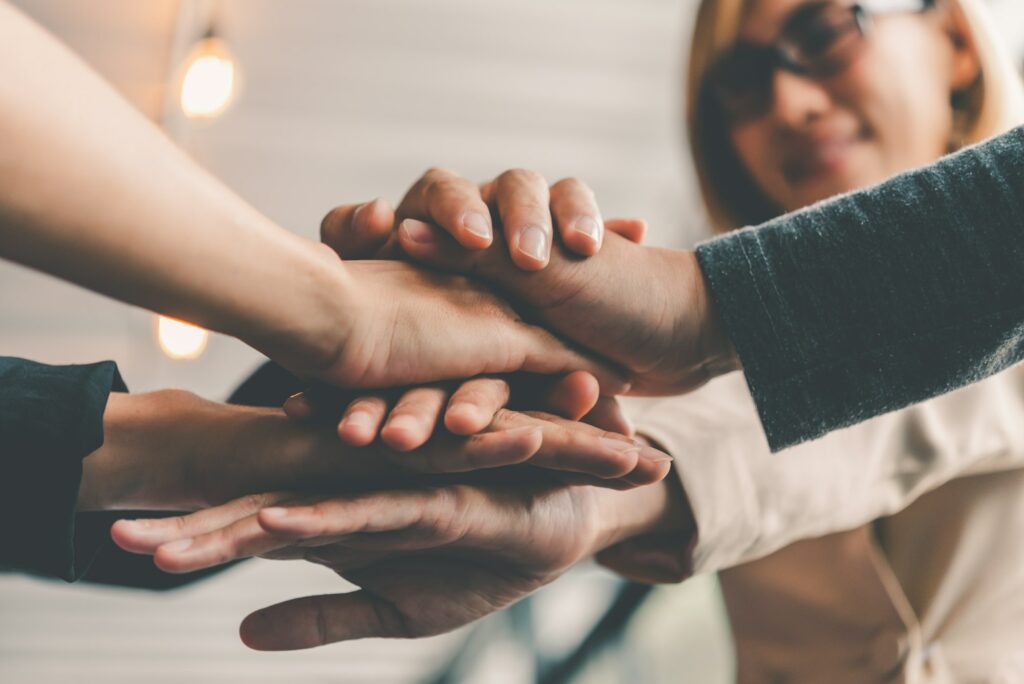 Hands of business people come together in a stack of hands to symbolize collaboration